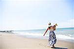 Rear view of mother carrying baby son on beach, Malibu, California, USA