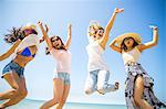 Four adult female friends jumping mid air on beach, Malibu, California, USA