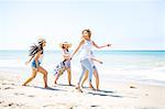 Four adult female friends fooling around on beach, Malibu, California, USA