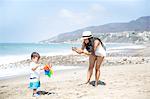 Mother photographing baby son on beach, Malibu, California, USA