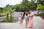 Women carrying baby daughter and sons moving up driveway, Malibu, California, USA