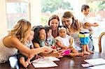 Woman taking selfie with mothers and babies at dining table