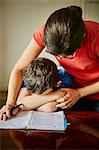 Mother comforting upset son doing homework