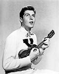 1940s 1950s COLLEGE BOY WEARING X LETTER SWEATER SINGING AND PLAYING UKULELE