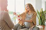 Smiling pregnant woman receiving gift from friend