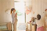 Pregnant mother and daughter decorating sunny nursery