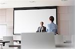 Businessman with microphone speaking to businesswoman in conference room