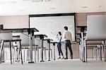 Businesswoman with microphone leading meeting at projection screen