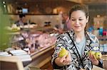 Smiling woman examining pears in market