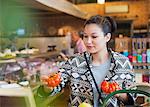 Woman shopping examining heirloom tomatoes in market