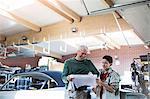 Father and son reviewing plans in auto repair shop