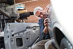 Focused auto body worker examining panel on car