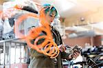 Young female mechanic with blue hair using equipment in auto repair shop