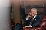 Smiling businessman talking on cell phone in menswear shop