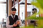 Well-dressed bartender examining whiskey bottle