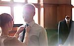 Tailor adjusting tie for businessman in menswear shop