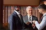 Tailor explaining suit to businessman in menswear shop