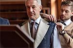 Tailor fitting businessman for suit in menswear shop