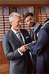 Tailor and businessman examining suit in menswear shop