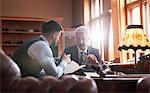 Tailor and businessman viewing fabric in menswear shop