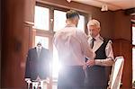 Tailor fitting businessman for suit in menswear shop