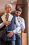 Tailor fitting businessman for suit in menswear shop