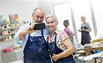 Senior couple taking selfie in pottery studio