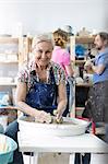 Portrait smiling senior woman using pottery wheel in studio