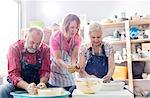 Teacher and senior couple using pottery wheels in studio