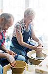 Senior couple using pottery wheels in studio