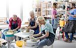 Mature students using pottery wheels in studio