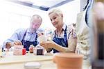 Senior couple painting pottery in studio