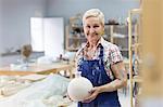 Portrait smiling senior woman holding pottery vase in studio