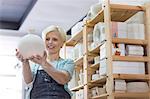 Smiling woman holding pottery vase in studio