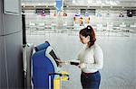 Traveller using self service check-in machine at airport