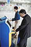 Business people using self service check-in machine at airport