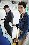 Businesswoman using self service check-in machine at airport