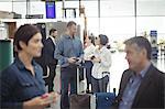 Business people holding boarding pass and using mobile phone in airport terminal