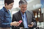 Business people holding boarding pass and using mobile phone in airport terminal