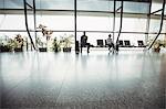 Business people sitting with luggage at waiting area in airport terminal