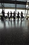 Business people using mobile phone in waiting area at airport terminal