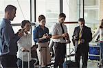 Business people using mobile phone in waiting area at airport terminal