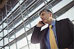 Businessman talking on mobile phone in waiting area at airport terminal