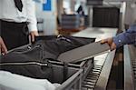 Man putting laptop into tray for security check at airport