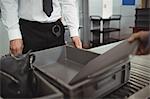 Man putting laptop into tray for airport security check in airport