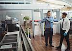 Airport security officer using a hand held metal detector to check a passenger in airport