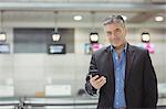 Businessman using mobile phone in waiting area at airport terminal