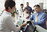 Airline check-in attendant handing boarding pass to passenger at airport check-in counter
