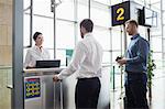 Man giving his passport to airline check-in attendant at airport check-in counter