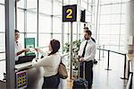 Woman giving her passport to airline check-in attendant at airport check-in counter